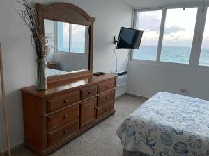 San Juan 1 BR Ocean Front Condo in Condado '8' في سان خوان: غرفة نوم مع خزانة مع مرآة وتلفزيون