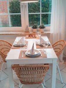una mesa blanca con sillas, platos y vasos. en Fewo Rosalie en Norddeich