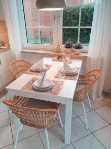 ノルトダイヒにあるFewo Rosalieの白いテーブル(椅子、皿、ワイングラス付)