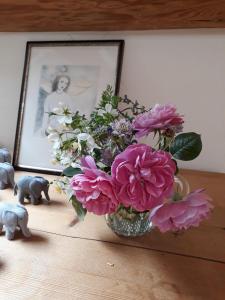 un jarrón de flores en una mesa con una foto en Chez Cathy en Arzier