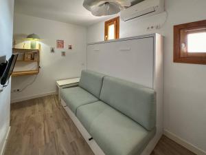 um sofá verde num quarto com um frigorífico em Tu estudio en el centro de Madrid em Madri