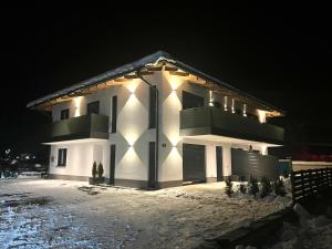 a white house with lights on it in the snow at Alpin Apartments in Radstadt