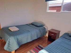 1 dormitorio con 2 camas, mesa y ventana en Cómodo departamento full equipado en Coyhaique, en Coyhaique