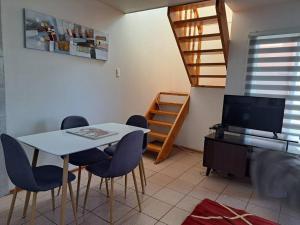 un comedor con mesa y sillas y una escalera en Cómodo departamento full equipado en Coyhaique, en Coyhaique