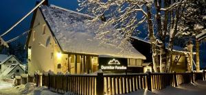 a building with a sign on it in the snow at Guest House Durmitor Paradise in Žabljak
