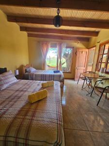 a bedroom with two beds and a table and a window at Hostal Casa los Duendes in San Pedro de Atacama