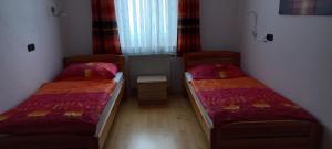 duas camas num pequeno quarto com lençóis vermelhos em Ferienwohnung by Pfleger's em Ulrichsberg