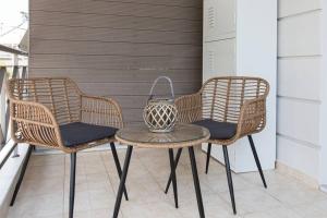 two wicker chairs and a table on a balcony at Virginia's Luxury Suite 4 in Volos