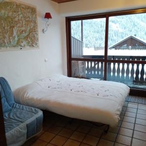 uma cama e uma cadeira num quarto com uma janela em Studio le Dahut em Champagny-en-Vanoise