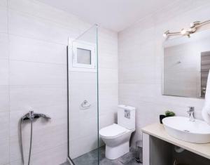 a white bathroom with a toilet and a sink at Stella Apartment in Kaloi Limenes