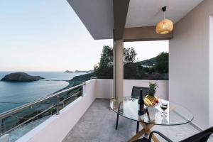 a glass table on a balcony with a view of the ocean at Stella Apartment in Kali Limenes