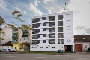 a white building with cars parked in front of it at Apartman IVANA - private parking in Osijek