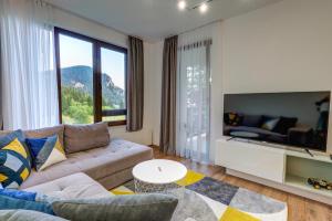 a living room with a couch and a large window at N.Joy Holiday Apartment 534 by Oak Residence in Smolyan