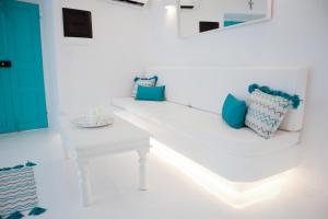 a white room with blue pillows on a white bench at The Turquoise House in the heart of Ioulida, on the island of Kea. in Ioulis