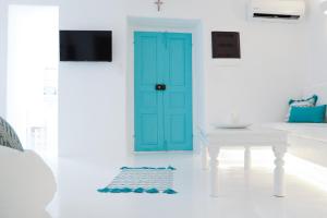 Una puerta azul en una habitación blanca con una mesa en The Turquoise House in the heart of Ioulida, on the island of Kea. en Kéa