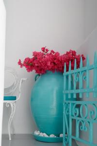 a blue vase with red flowers in it at The Turquoise House in the heart of Ioulida, on the island of Kea. in Ioulis
