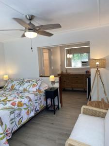 a bedroom with a bed and a bathroom with a ceiling fan at Alexander Palms Court - No Hidden Resort Fees! in Key West
