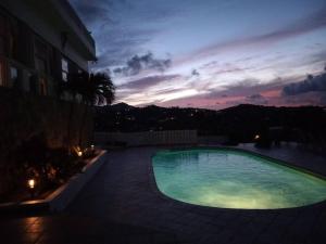 una piscina por la noche con una puesta de sol en el fondo en Breathtaking ocean views in Judiths Fancy en La Grande Princesse