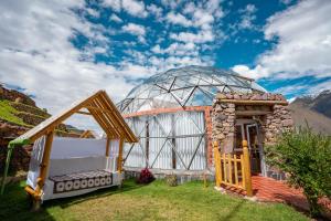 a glass dome house with a bed in the grass at StarDomeLodge in Ollantaytambo