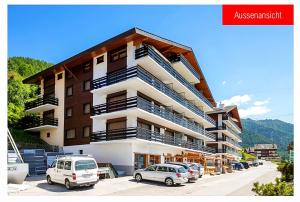 a large building with cars parked in a parking lot at ''Chalet'' au Centre et Parking Couvert GRATUIT in Veysonnaz