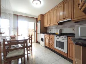 a kitchen with wooden cabinets and a table and a dining room at Espectaculares vistas Mirador Alameda con Garaje in Ourense