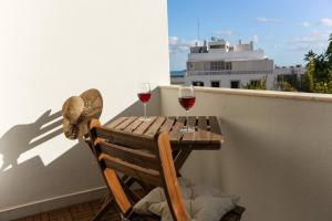 - une table en bois avec deux verres de vin sur le balcon dans l'établissement Gyula Old Town Apartment, à Albufeira