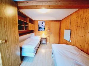 two beds in a room with wooden walls at Höflihaus, Maienfeld in Maienfeld