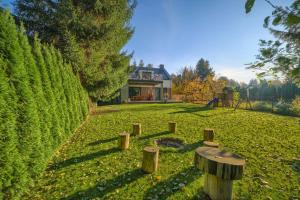 un jardin avec des boiseries dans l'herbe et une maison dans l'établissement ArtHouse Pelnik, à Łukta