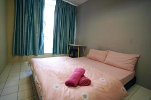 a pink stuffed animal laying on a bed at Swanling Kuching in Kuching