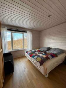ein Schlafzimmer mit einem Bett in einem Zimmer mit einem Fenster in der Unterkunft Feriehus med ti senger på Skaidi in Hammerfest