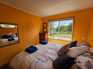 1 dormitorio con 1 cama grande y espejo en Hermosa cabaña con orilla de playa y tinaja en Lago Frío en Coihaique