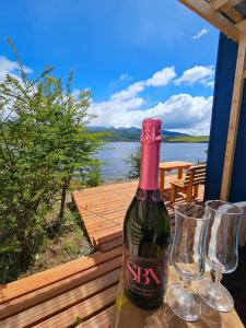 una botella de vino sentada en una mesa con dos copas en Hermosa cabaña con orilla de playa y tinaja en Lago Frío en Coihaique