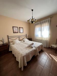 1 dormitorio con 1 cama con manta blanca y ventana en Casa rural Con Calma, en Zarzuela del Monte