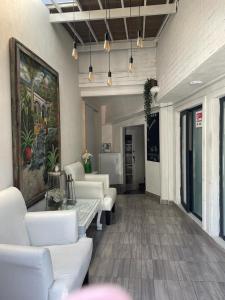 a living room with white couches and a painting on the wall at Villa GyG in Mexico City