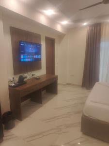 Zimmer mit einem Schreibtisch, einem TV und einem Bett in der Unterkunft PK Boutique Hotel in Noida