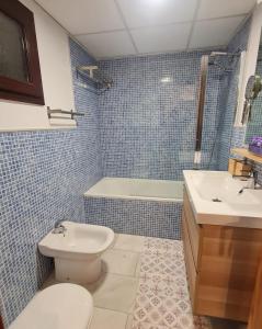 a blue tiled bathroom with a toilet and a sink at Apartamento Alfa con parking y wifi by SURYNIEVE in Sierra Nevada