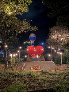 Una statua di un cuore rosso con un orologio in un parco di notte di Hostel paraiso de colores a Popayan