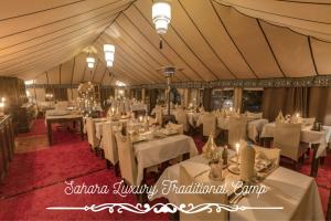 Una carpa comedor con mesas y sillas blancas. en Sahara Luxury Traditional Camp, en Merzouga
