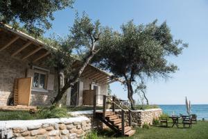 een huis aan het water met een tafel en stoelen bij La Baia Guest House in Karítsa