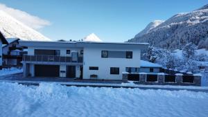 een huis in de sneeuw met bergen op de achtergrond bij Apart Emilia in Schönwies