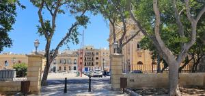 a building with a gate and trees in front of it at Near Valletta City - Open Views - Ta Tessie Suite in Floriana - Malta in Il-Furjana