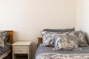 ein Bett mit zwei Kissen und ein Nachttisch daneben in der Unterkunft Cosy Retreat - SmartTV and Wi-Fi in Gillingham