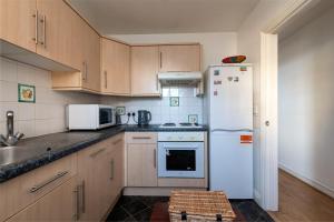 cocina con armarios de madera y nevera blanca en Cosy Retreat - SmartTV and Wi-Fi en Gillingham