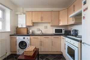 eine Küche mit einer Waschmaschine und einer Mikrowelle in der Unterkunft Cosy Retreat - SmartTV and Wi-Fi in Gillingham