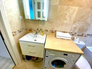 a bathroom with a sink and a washing machine at Apartament Sara in Iaşi