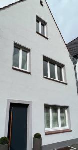 um edifício branco com três janelas e uma porta azul em Premium Apartment mit Domblick im DG em Paderborn