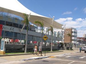 two people crossing a street in front of a building at Mardisa Flat Frente Mar in João Pessoa