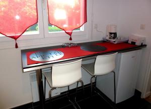 リヨンにあるAppartement Monplaisir Part Dieuのキッチン(赤いカウンター、白い椅子付)