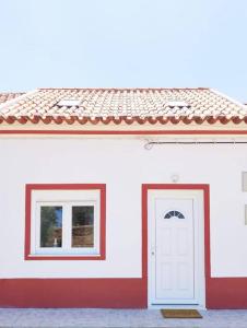 un edificio blanco con dos ventanas y una puerta blanca en Casinha da Avó en Santiago do Cacém