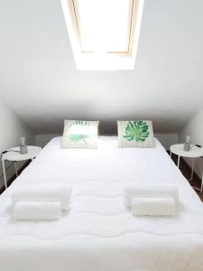 Casinha da Avó في سانتياغو دو كاسيم: سرير أبيض كبير مع وسادتين ونافذة
